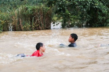 Pekan, Malezya - 12 Ocak 2021: Bir grup çocuk yolda sel sularında oynuyorlar.