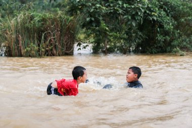 Pekan, Malezya - 12 Ocak 2021: Bir grup çocuk yolda sel sularında oynuyorlar.