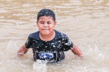 Pekan, Malezya - 12 Ocak 2021: Sel suyunda su sıçratan Asyalı çocuk