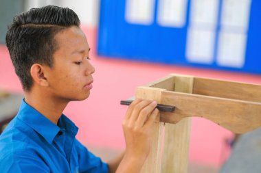 İş kıyafetleri içindeki genç marangoz atölyedeki konsol tablosunun saldırganlık bileşenlerinde kare kullanmayı deniyor.