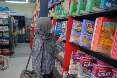 Kuantan, Malezya - 12 Aralık 2020: Başörtülü kadınlar kitapçıda kitap seçiyorlar