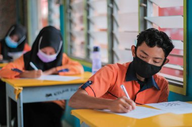 Muadzam Şah, Malezya - 20 Ocak 2021: Malezyalı öğrenciler Covid -19 'dan korunmak için sınıfta yüz maskesi ve yüz maskesi takıyorlar. Yeni normal eğitim.