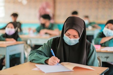 Muadzam Şah, Malezya - 20 Ocak 2021: Malezyalı öğrenciler Covid -19 'dan korunmak için sınıfta yüz maskesi ve yüz maskesi takıyorlar. Yeni normal eğitim.