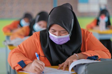 Muadzam Şah, Malezya - 20 Ocak 2021: Malezyalı öğrenciler Covid -19 'dan korunmak için sınıfta yüz maskesi ve yüz maskesi takıyorlar. Yeni normal eğitim.