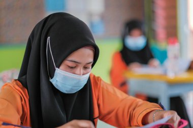 Muadzam Şah, Malezya - 20 Ocak 2021: Malezyalı öğrenciler Covid -19 'dan korunmak için sınıfta yüz maskesi ve yüz maskesi takıyorlar. Yeni normal eğitim.