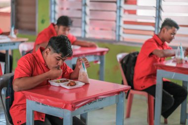 Muadzam Şah, Malezya - 20 Ocak 2021: Öğrenci sınıfta yemek yiyor. Sosyal uzaklık. Corona virüsünün ya da COVID 'nin korunmasını kabul et - 19.