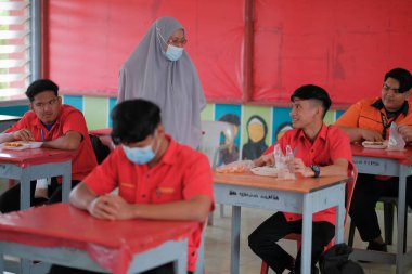 Muadzam Şah, Malezya - 20 Ocak 2021: Öğrenci ve öğrenci sınıfta yemek yiyor. Sosyal uzaklık. Corona virüsünün ya da COVID 'nin korunmasını kabul et - 19.