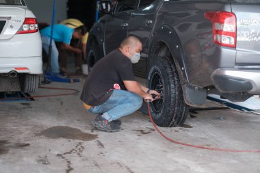 Kuala Lumpur, Malezya - 29 Haziran 2020: Tamir istasyonunun garajında pnömatik ingiliz anahtarıyla lastik veya tekerlek değiştirme yapan araba tamircisi