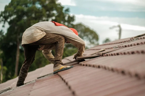 Workers installing roof tile. Construction of a house roof, ceramic tile or concrete  roof tile industry