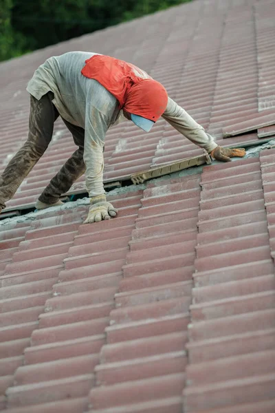 Workers installing roof tile. Construction of a house roof, ceramic tile or concrete  roof tile industry