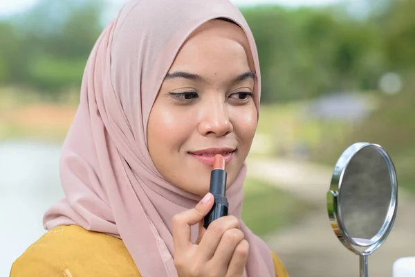 Bulanık arka planda ruj süren tesettür takan güzel Müslüman kadın..