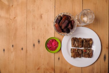 Geleneksel İslami Ramazan veya Ramazan iftar yemekleri. Düz hurma yatağı ve Murtabak ahşap zemin üzerinde taze içme suyu, üst manzara. Ramazan Müslüman oruç ayı