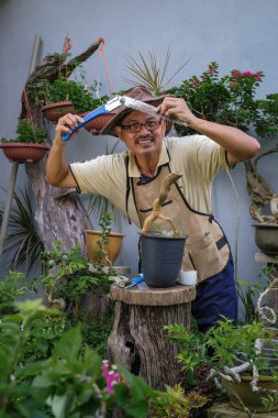 Bir adam bahçede adım adım Bougainvillea çiçeği naklediyor.