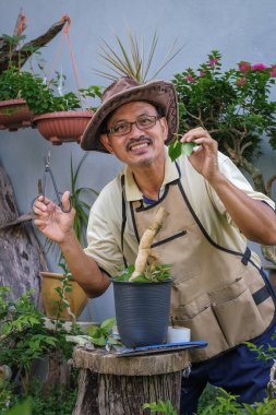 Bir adam bahçede adım adım Bougainvillea çiçeği naklediyor.