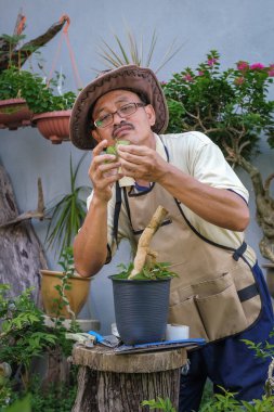 Bir adam bahçede adım adım Bougainvillea çiçeği naklediyor.