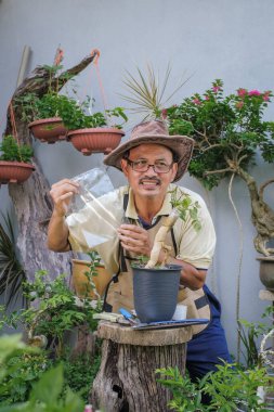 Bir adam bahçede adım adım Bougainvillea çiçeği naklediyor.