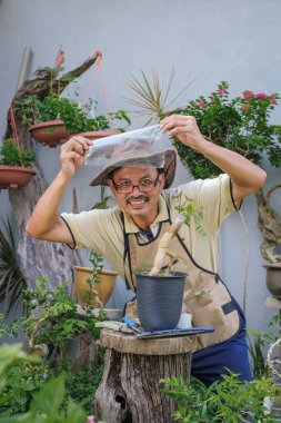 Bir adam bahçede adım adım Bougainvillea çiçeği naklediyor.