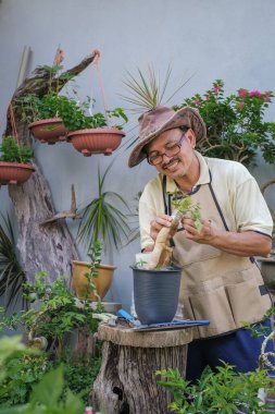 Bir adam bahçede adım adım Bougainvillea çiçeği naklediyor.