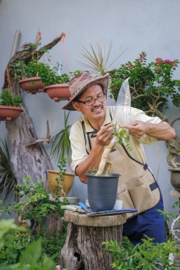 Bir adam bahçede adım adım Bougainvillea çiçeği naklediyor.