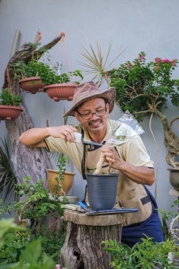 Bir adam bahçede adım adım Bougainvillea çiçeği naklediyor.