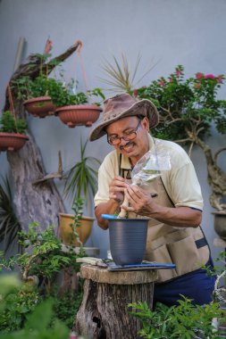 Bir adam bahçede adım adım Bougainvillea çiçeği naklediyor.