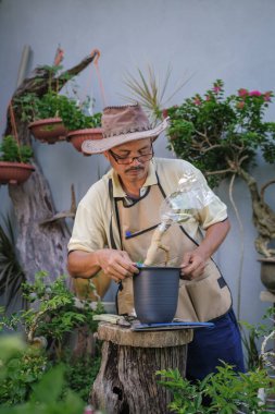 Bir adam bahçede adım adım Bougainvillea çiçeği naklediyor.