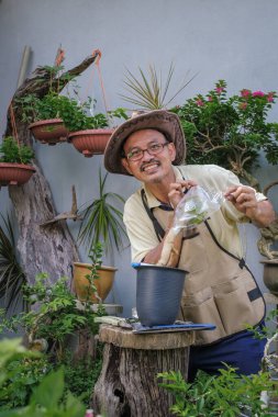 Bir adam bahçede adım adım Bougainvillea çiçeği naklediyor.