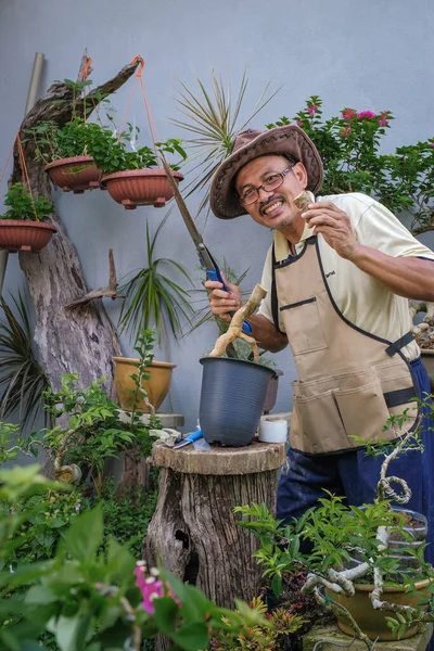 Bir adam bahçede adım adım Bougainvillea çiçeği naklediyor.