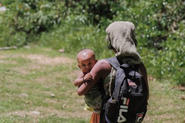 Muadzam Şah, Malezya - 2 Haziran 2021: Güneşli bir günde bebeğini taşıyan Aborjin anne.