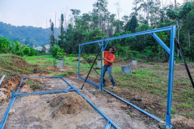 Bahçıvanlar bahçede c kanalı çeliğinden bebek odası yapıları inşa ederken kablosuz tornavida ve ruh seviyesini kullanıyorlar..