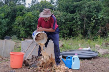  Olgun bir adam meyve bahçesindeki bahçe komposterine mutfak atıkları atıyor. .