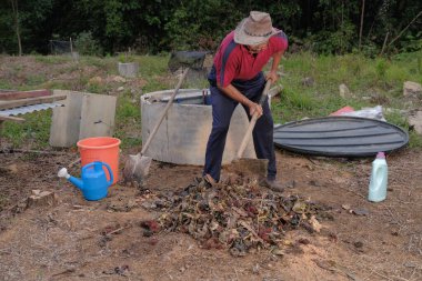 Çapa kullanan olgun bir adam. Erkek bahçıvan dönüşür, gübre yığını bahçedeki karışımı gevşetip yardım havasını yumuşatır. Çevre dostu evler kavramı