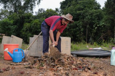 Çapa kullanan olgun bir adam. Erkek bahçıvan dönüşür, gübre yığını bahçedeki karışımı gevşetip yardım havasını yumuşatır. Çevre dostu evler kavramı