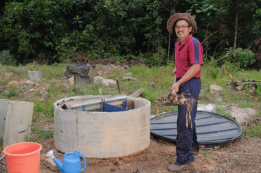 Bahçe kepçesi kullanan olgun bir adam. Erkek bahçıvan dönüşür, gübre yığını bahçedeki karışımı gevşetip yardım havasını yumuşatır. Çevre dostu evler kavramı