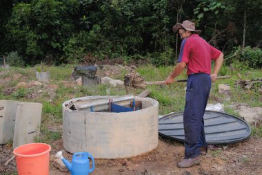 Bahçe kepçesi kullanan olgun bir adam. Erkek bahçıvan dönüşür, gübre yığını bahçedeki karışımı gevşetip yardım havasını yumuşatır. Çevre dostu evler kavramı