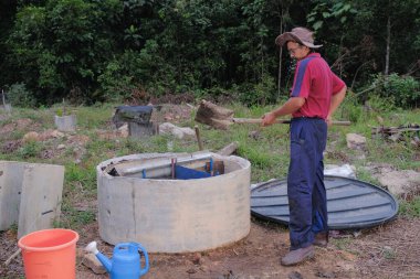 Bahçe kepçesi kullanan olgun bir adam. Erkek bahçıvan dönüşür, gübre yığını bahçedeki karışımı gevşetip yardım havasını yumuşatır. Çevre dostu evler kavramı