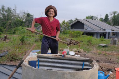 Bahçe kepçesi kullanan olgun bir adam. Erkek bahçıvan dönüşür, gübre yığını bahçedeki karışımı gevşetip yardım havasını yumuşatır. Çevre dostu evler kavramı