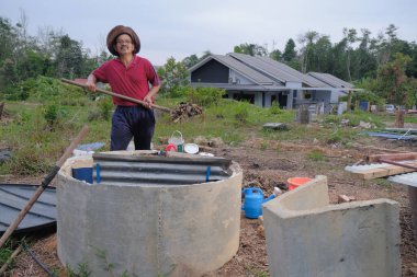 Bahçe kepçesi kullanan olgun bir adam. Erkek bahçıvan dönüşür, gübre yığını bahçedeki karışımı gevşetip yardım havasını yumuşatır. Çevre dostu evler kavramı