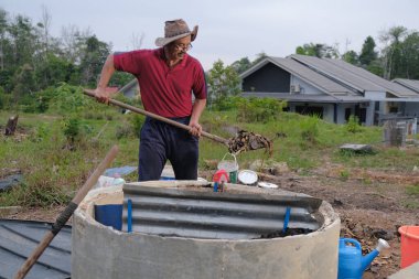 Bahçe kepçesi kullanan olgun bir adam. Erkek bahçıvan dönüşür, gübre yığını bahçedeki karışımı gevşetip yardım havasını yumuşatır. Çevre dostu evler kavramı
