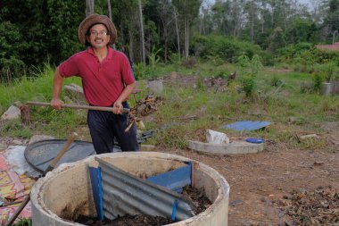 Bahçe kepçesi kullanan olgun bir adam. Erkek bahçıvan dönüşür, gübre yığını bahçedeki karışımı gevşetip yardım havasını yumuşatır. Çevre dostu evler kavramı