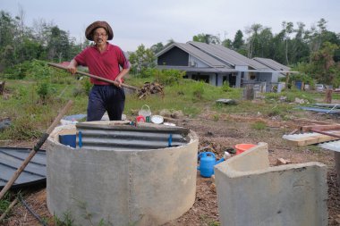 Bahçe kepçesi kullanan olgun bir adam. Erkek bahçıvan dönüşür, gübre yığını bahçedeki karışımı gevşetip yardım havasını yumuşatır. Çevre dostu evler kavramı