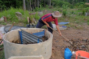 Bahçe kepçesi kullanan olgun bir adam. Erkek bahçıvan dönüşür, gübre yığını bahçedeki karışımı gevşetip yardım havasını yumuşatır. Çevre dostu evler kavramı