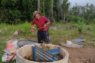 Bahçe kepçesi kullanan olgun bir adam. Erkek bahçıvan dönüşür, gübre yığını bahçedeki karışımı gevşetip yardım havasını yumuşatır. Çevre dostu evler kavramı