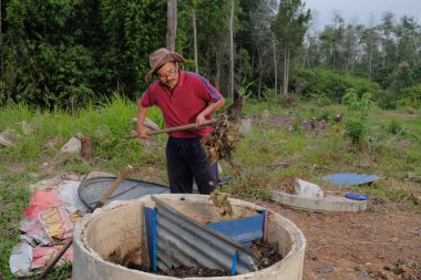 Bahçe kepçesi kullanan olgun bir adam. Erkek bahçıvan dönüşür, gübre yığını bahçedeki karışımı gevşetip yardım havasını yumuşatır. Çevre dostu evler kavramı