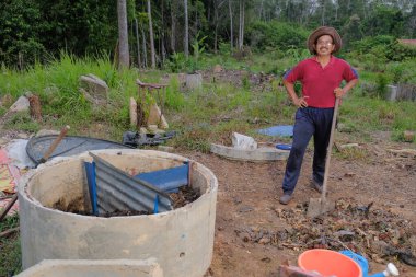 Bahçe kepçesi kullanan olgun bir adam. Erkek bahçıvan dönüşür, gübre yığını bahçedeki karışımı gevşetip yardım havasını yumuşatır. Çevre dostu evler kavramı