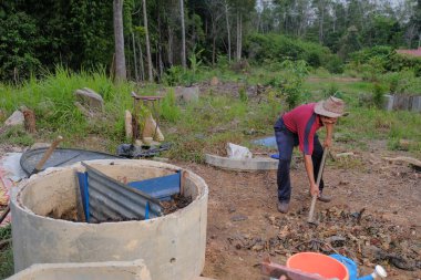 Bahçe kepçesi kullanan olgun bir adam. Erkek bahçıvan dönüşür, gübre yığını bahçedeki karışımı gevşetip yardım havasını yumuşatır. Çevre dostu evler kavramı