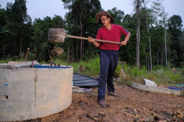 Bahçe kepçesi kullanan olgun bir adam. Erkek bahçıvan dönüşür, gübre yığını bahçedeki karışımı gevşetip yardım havasını yumuşatır. Çevre dostu evler kavramı