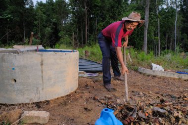 Bahçe kepçesi kullanan olgun bir adam. Erkek bahçıvan dönüşür, gübre yığını bahçedeki karışımı gevşetip yardım havasını yumuşatır. Çevre dostu evler kavramı