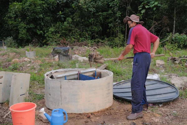 Bahçe kepçesi kullanan olgun bir adam. Erkek bahçıvan dönüşür, gübre yığını bahçedeki karışımı gevşetip yardım havasını yumuşatır. Çevre dostu evler kavramı