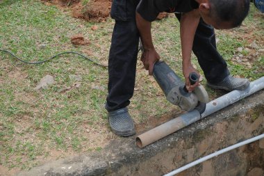 Muadzam Shah, Malezya - 1 Eylül 2021: Tesisatçı, ana drenajda yeni HDPE çalışmaları için öğütücü makine kullanıyor